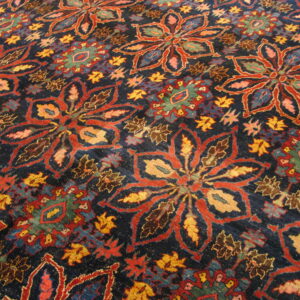 Close view of a richly patterned, dark blue rug featuring large stylized flowers in red and gold.
