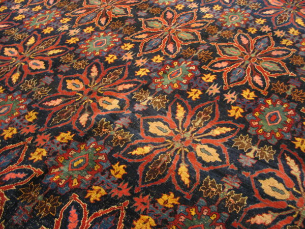 Close view of a richly patterned, dark blue rug featuring large stylized flowers in red and gold.