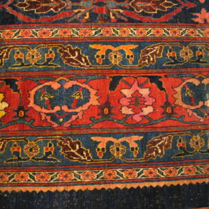 Detailed view of a rug's banded pattern in navy, rust, and colorful stylized floral designs.