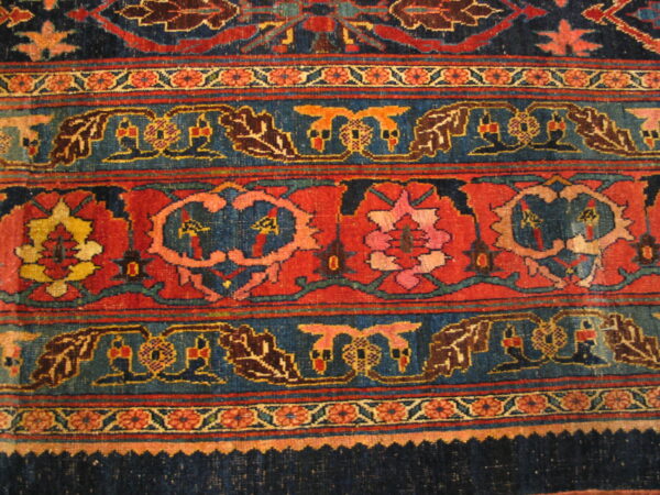 Detailed view of a rug's banded pattern in navy, rust, and colorful stylized floral designs.