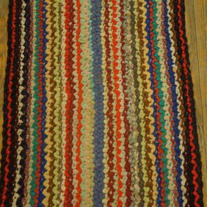 Close-up of a thick, braided runner rug with multicolored vertical stripes on a wood floor.