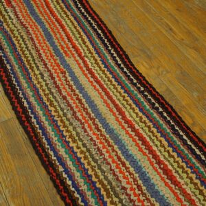 Braided runner rug featuring vibrant multicolored stripes sits on light, worn hardwood planks.