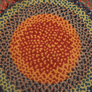 Multicolor braided round rug with concentric bands of red, orange, yellow, blue, and patterned braids.