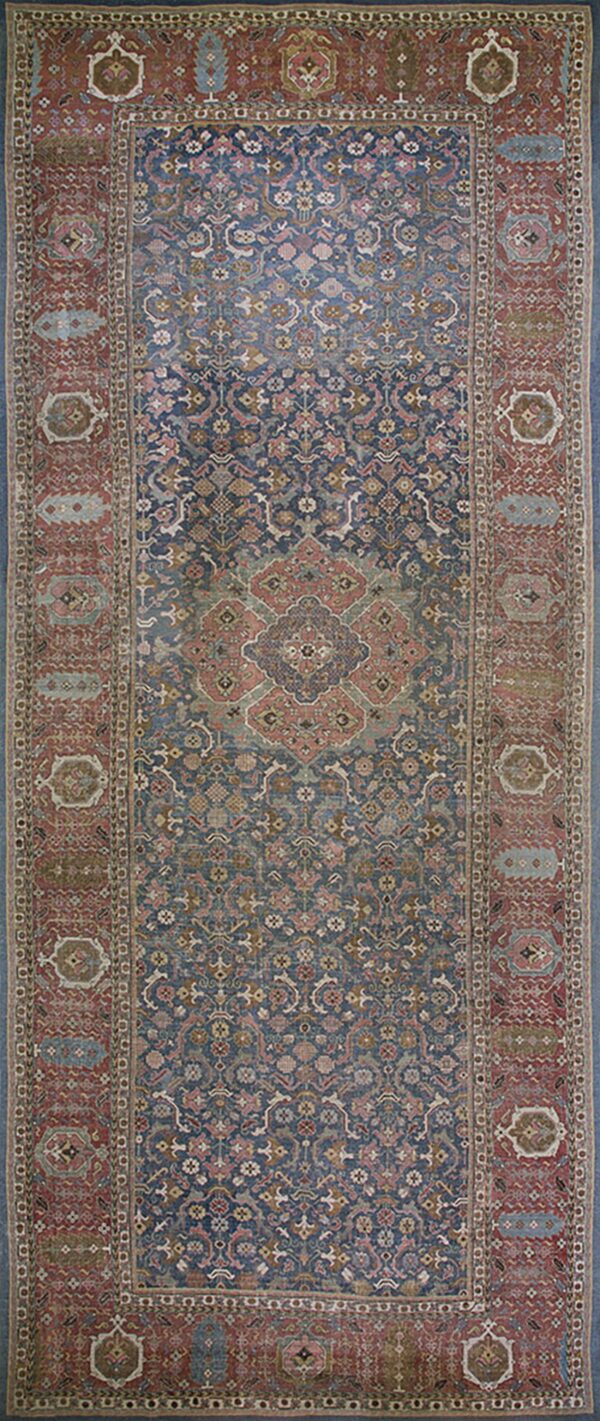 Runner rug with a blue central field, a prominent medallion, and densely patterned red borders.