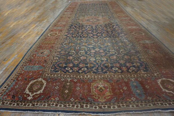 A long patterned rug, featuring deep blue and rust colors, rests on wide, distressed wood planks.
