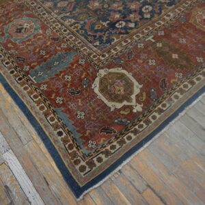 Low-pile red and navy patterned rug border rests on worn yellow and gray wooden floorboards.