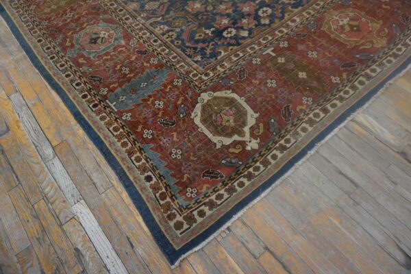 Low-pile red and navy patterned rug border rests on worn yellow and gray wooden floorboards.