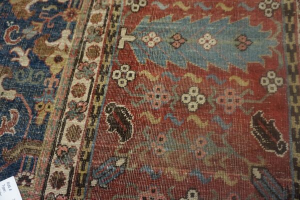 Woven rug detail showing red, navy, and teal patterns, including stylized motifs and a multi-striped border.