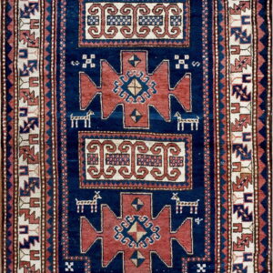 Rectangular blue rug featuring rust red medallions, cream scrolling motifs, and complex geometric borders.