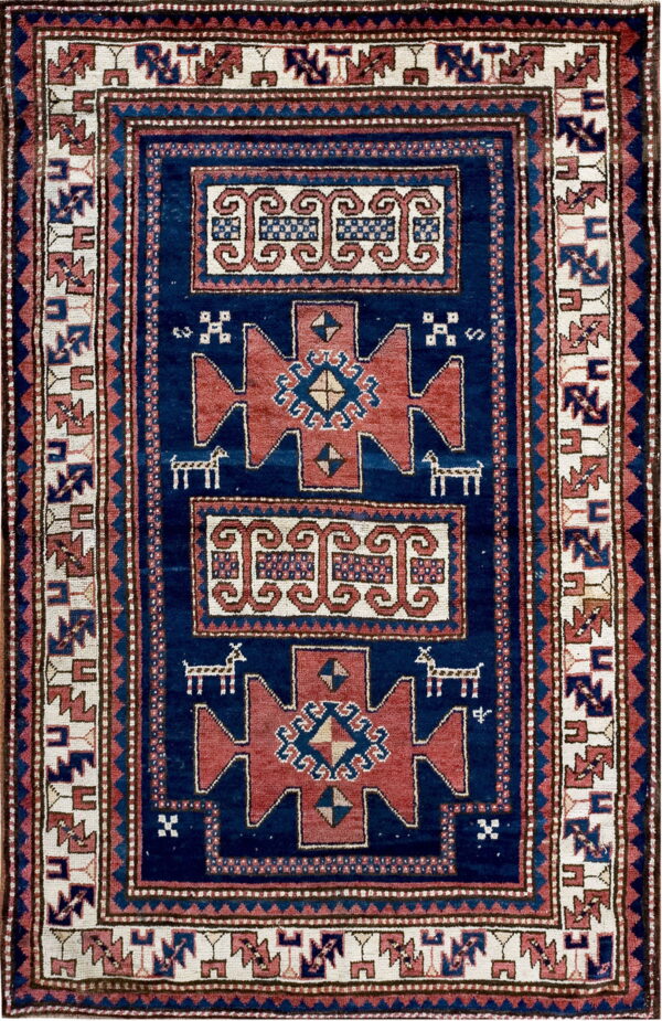 Rectangular blue rug featuring rust red medallions, cream scrolling motifs, and complex geometric borders.