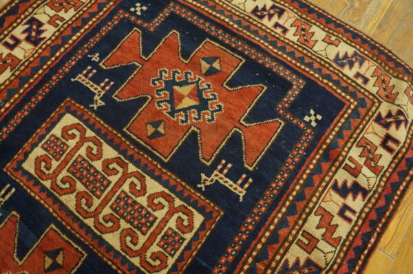 Navy, red, and cream geometric rug with a central stepped design visible on wood flooring.