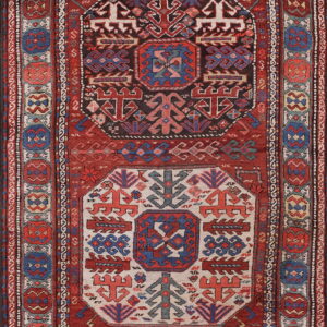 Red and navy tribal rug with ivory and dark geometric center medallions and patterned borders.