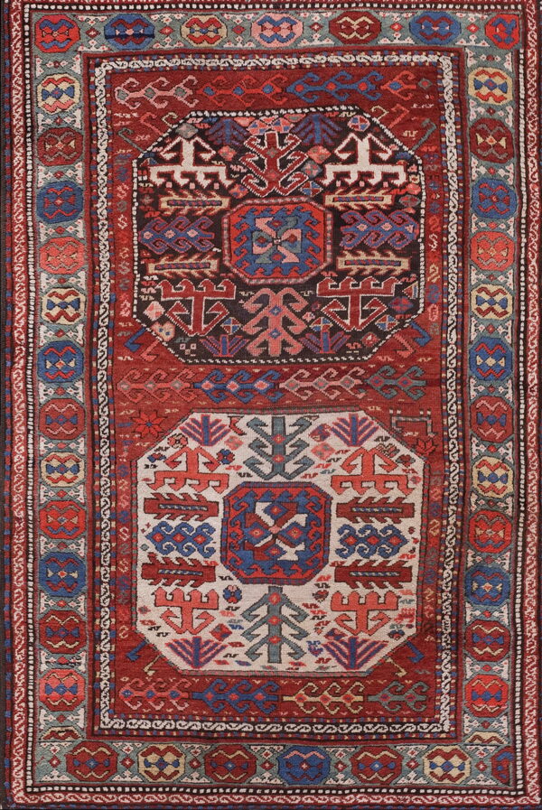 Red and navy tribal rug with ivory and dark geometric center medallions and patterned borders.