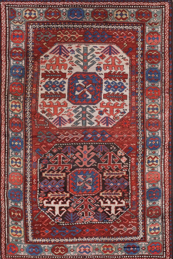 Red and navy tribal rug with ivory and dark geometric center medallions and patterned borders.