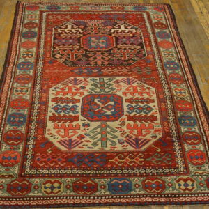 Rust red runner rug with geometric blue and cream medallions rests on wide plank wooden floorboards.