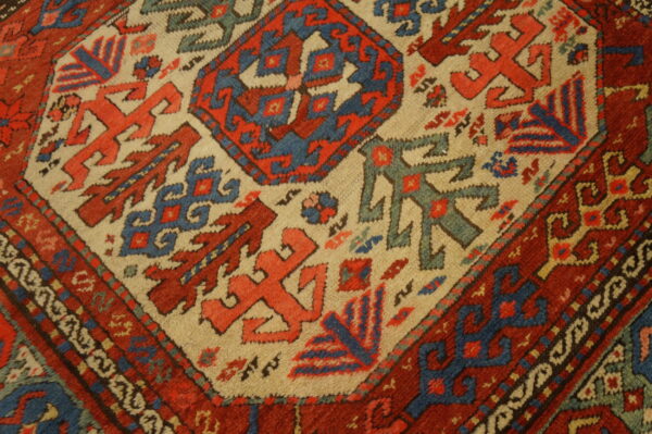 Thick pile rug featuring high-contrast geometric tribal patterns in deep red, blue, and light tan.