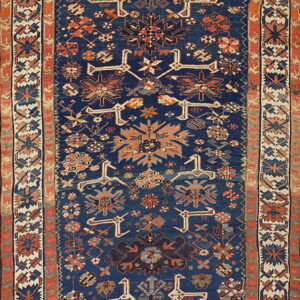 Geometric runner rug with a navy blue field, contrasting ivory border, and rust and tan tribal motifs.