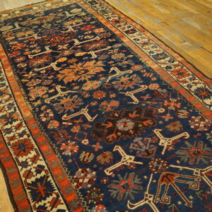 A long, low-pile runner with a navy and rust geometric pattern is displayed on light wood flooring.