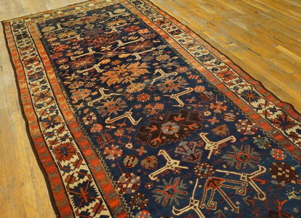 A long, low-pile runner with a navy and rust geometric pattern is displayed on light wood flooring.
