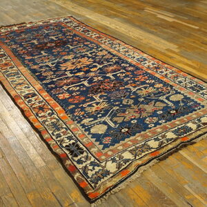 Traditional blue, orange, and cream patterned runner rug lying on rustic distressed wood planks.