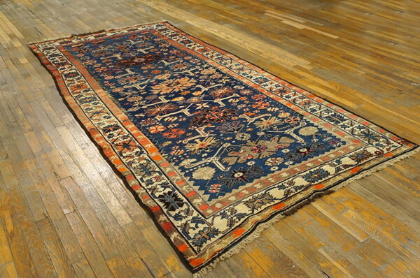 Traditional blue, orange, and cream patterned runner rug lying on rustic distressed wood planks.