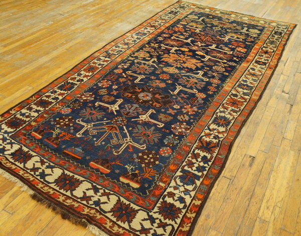 Navy runner rug with geometric designs in rust, cream, and orange on distressed hardwood flooring.