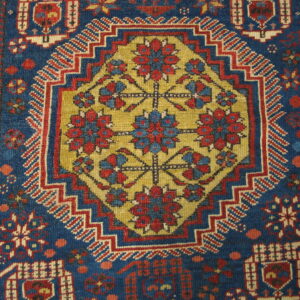 Geometric rug detail in deep blue, red, and gold, with a central stylized floral octagon motif.