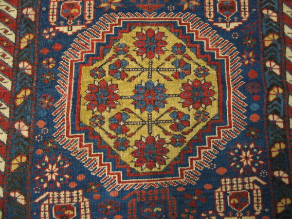 Geometric rug detail in deep blue, red, and gold, with a central stylized floral octagon motif.