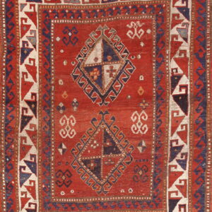 Low-pile red rug featuring geometric medallions and intricate borders in cream, navy, and rust colors.