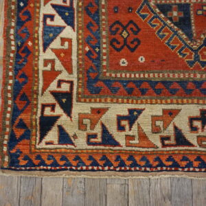 Geometric red, blue, and cream patterned rug border shown on rustic, gray wooden planks.