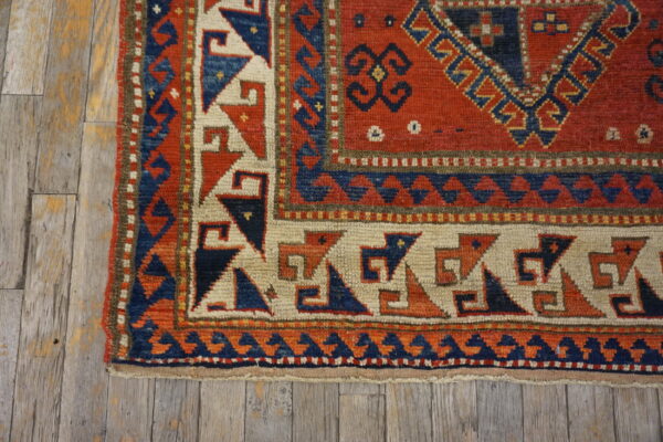 Geometric red, blue, and cream patterned rug border shown on rustic, gray wooden planks.