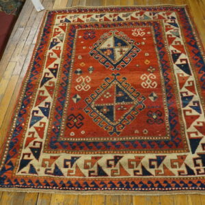 Geometric red rug featuring blue and beige accents and diamond designs on hardwood flooring.