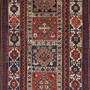 Low-pile geometric rug in navy blue, red, and cream featuring stacked central medallions and wide borders.