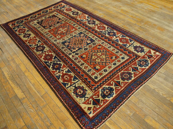 Rectangular rug featuring geometric panels in rust, navy, and cream on natural wooden planks.