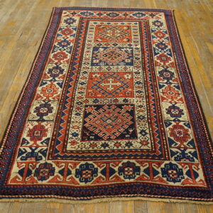 Low-pile geometric runner rug in red, indigo, and cream on distressed golden wood flooring.