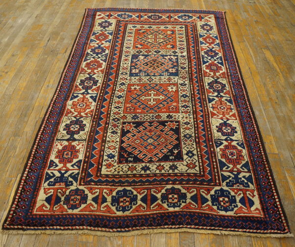 Low-pile geometric runner rug in red, indigo, and cream on distressed golden wood flooring.