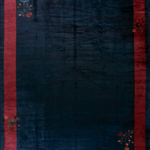 Plush dark blue rug with a magenta border featuring small colorful floral corner designs on wood.