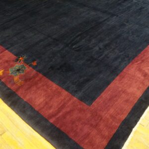 Plush navy rug corner with a thick burgundy border and blue floral motif on bright wood floors.