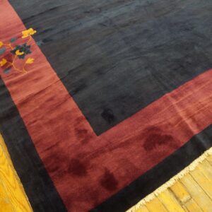 Plush dark blue rug with a maroon corner border and yellow floral detail on golden hardwood floors.