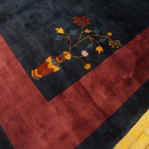 A plush navy rug with a maroon border shows a multicolored floral vase pattern on light wood.