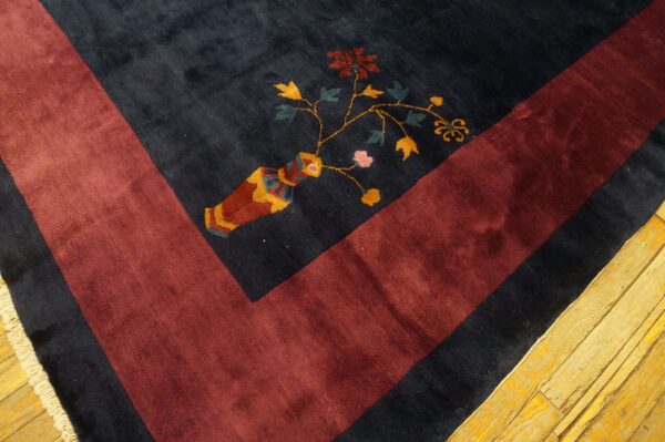 A plush navy rug with a maroon border shows a multicolored floral vase pattern on light wood.