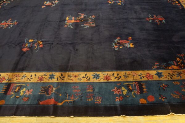 High-pile dark blue rug featuring scattered pictorials and detailed floral borders on a wood floor.