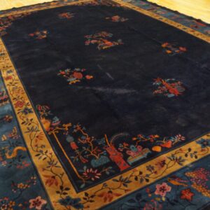 High-pile navy rug with detailed floral and ornamental borders rests on light yellow wood flooring.