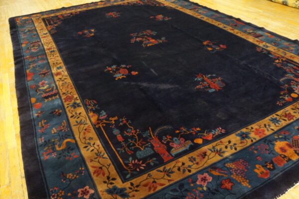 High-pile navy rug with detailed floral and ornamental borders rests on light yellow wood flooring.