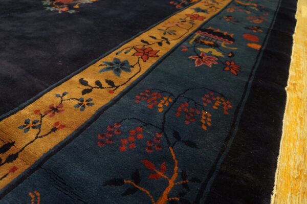Plush rug detail showing navy, gold, and teal borders with detailed floral and vine patterns over wood flooring.