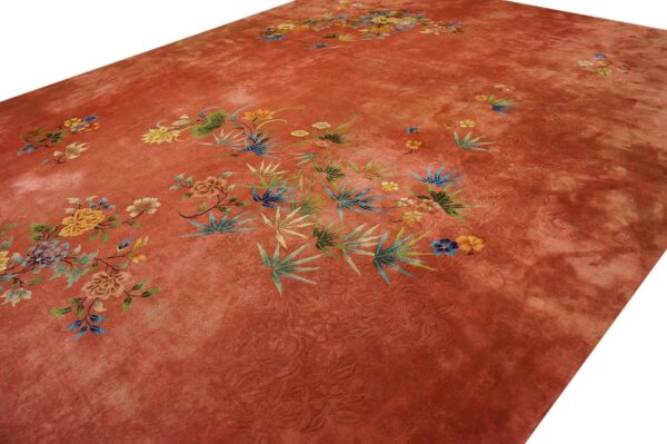 Rust-toned rug with subtle carving and scattered multicolored botanical and floral designs.