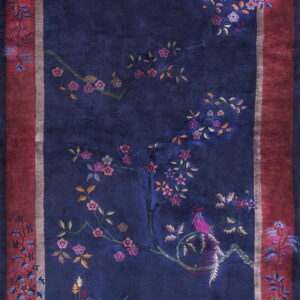 Plush navy rug displaying an ornate floral and bird motif surrounded by a wide burgundy border.
