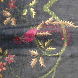 Dark blue rug detail shows a colorful botanical design with pink flowers, tan leaves, and green vines.