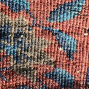 Low-pile texture close-up featuring red, navy, and blue floral motifs next to a contrasting blue rug.