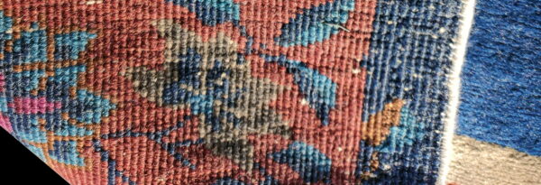 Low-pile texture close-up featuring red, navy, and blue floral motifs next to a contrasting blue rug.
